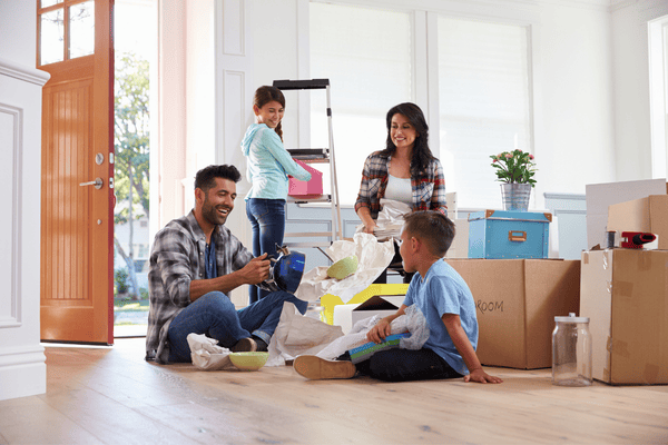 Family unpacking moving boxes together in a bright home.