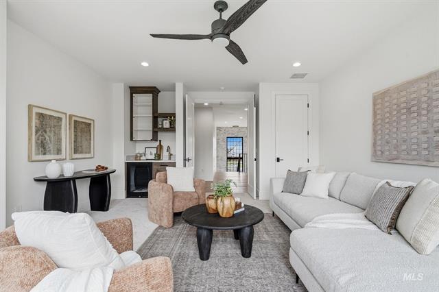 Furnished living room with a gray sectional, round black coffee table, and ceiling fan.