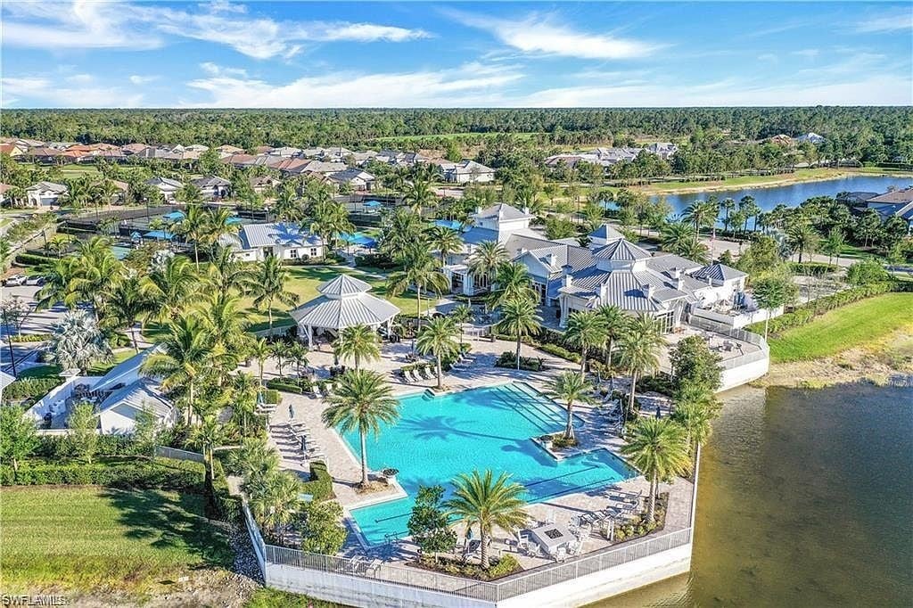 Resort-style pool and clubhouse surrounded by palm trees in Greyhawk at Golf Club of the Everglades, Naples FL