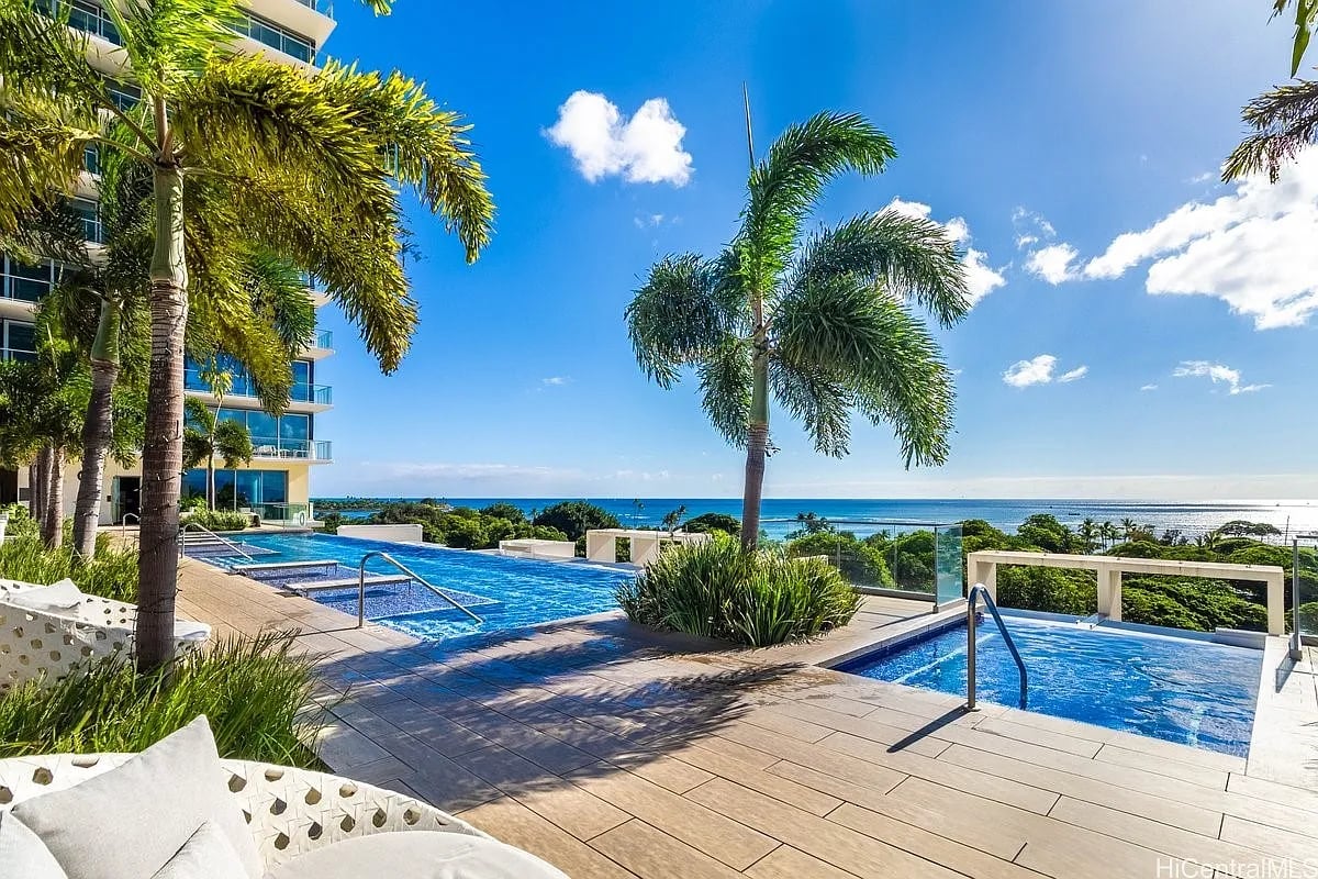 Condominium pool terrace with palm trees and ocean views.