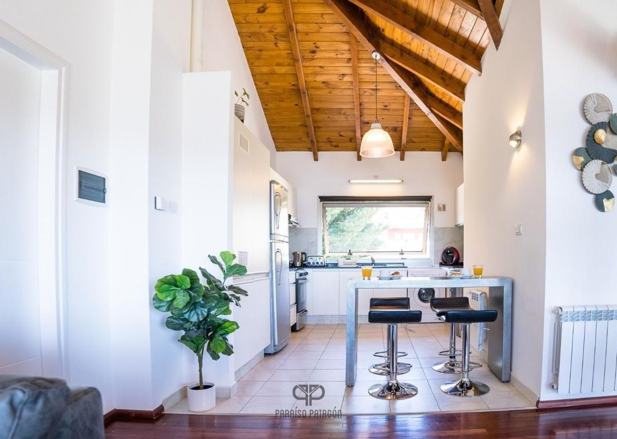 Kitchen with a vaulted wooden ceiling, stainless-steel appliances, and a breakfast bar with chrome stools.