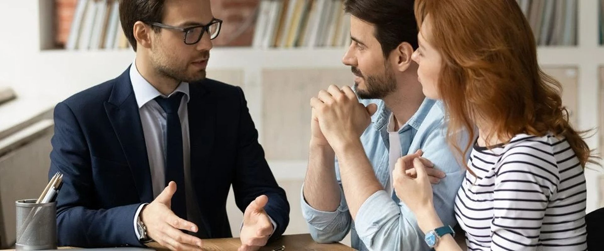 Real estate agent discusses a home sale with a couple in an office.