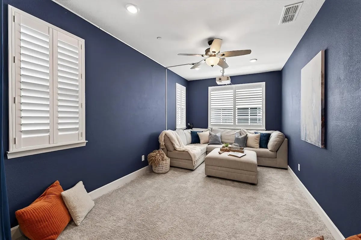 Media room with navy walls, a sectional sofa, and a ceiling-mounted projector.