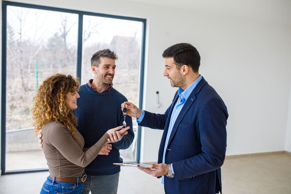 Real estate agent handing house keys to new homeowners during closing