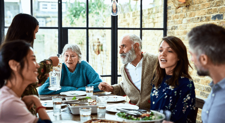 A diverse group of individuals gathered around a table, enjoying a meal together in a warm and inviting setting.