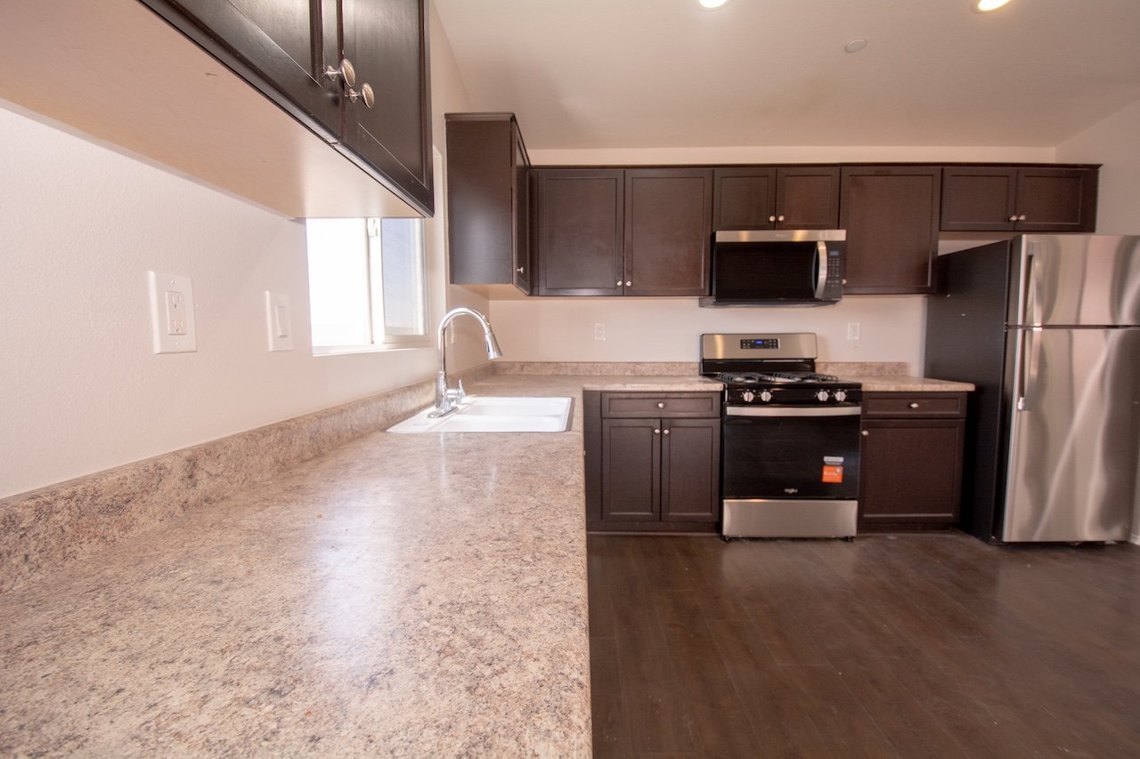 Kitchen with dark wood cabinets, speckled countertops, and stainless steel appliances.