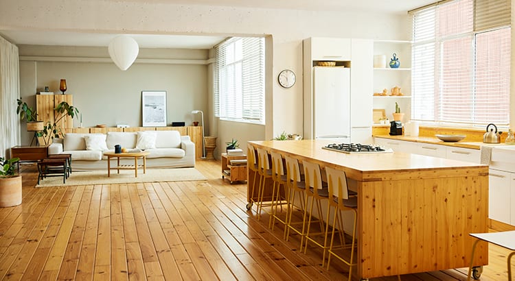 A spacious and modern kitchen with wooden flooring, large windows, and a dining area. The room is bright and inviting, highlighting contemporary home design.