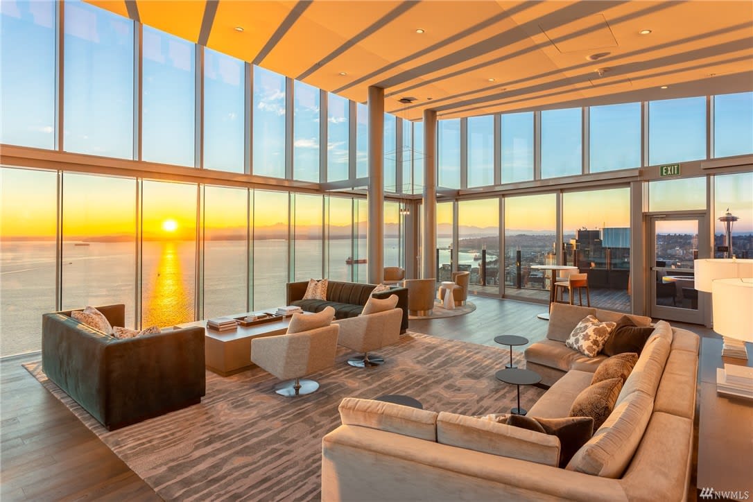 A cozy living room with a stunning sunset view through large windows.