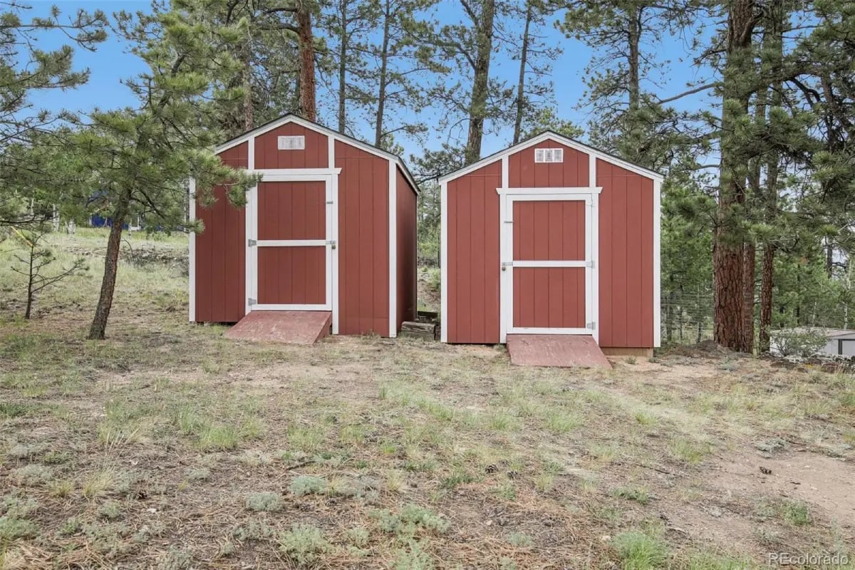 Dual red storage sheds surrounded by pine trees at 278 Overlook Drive.