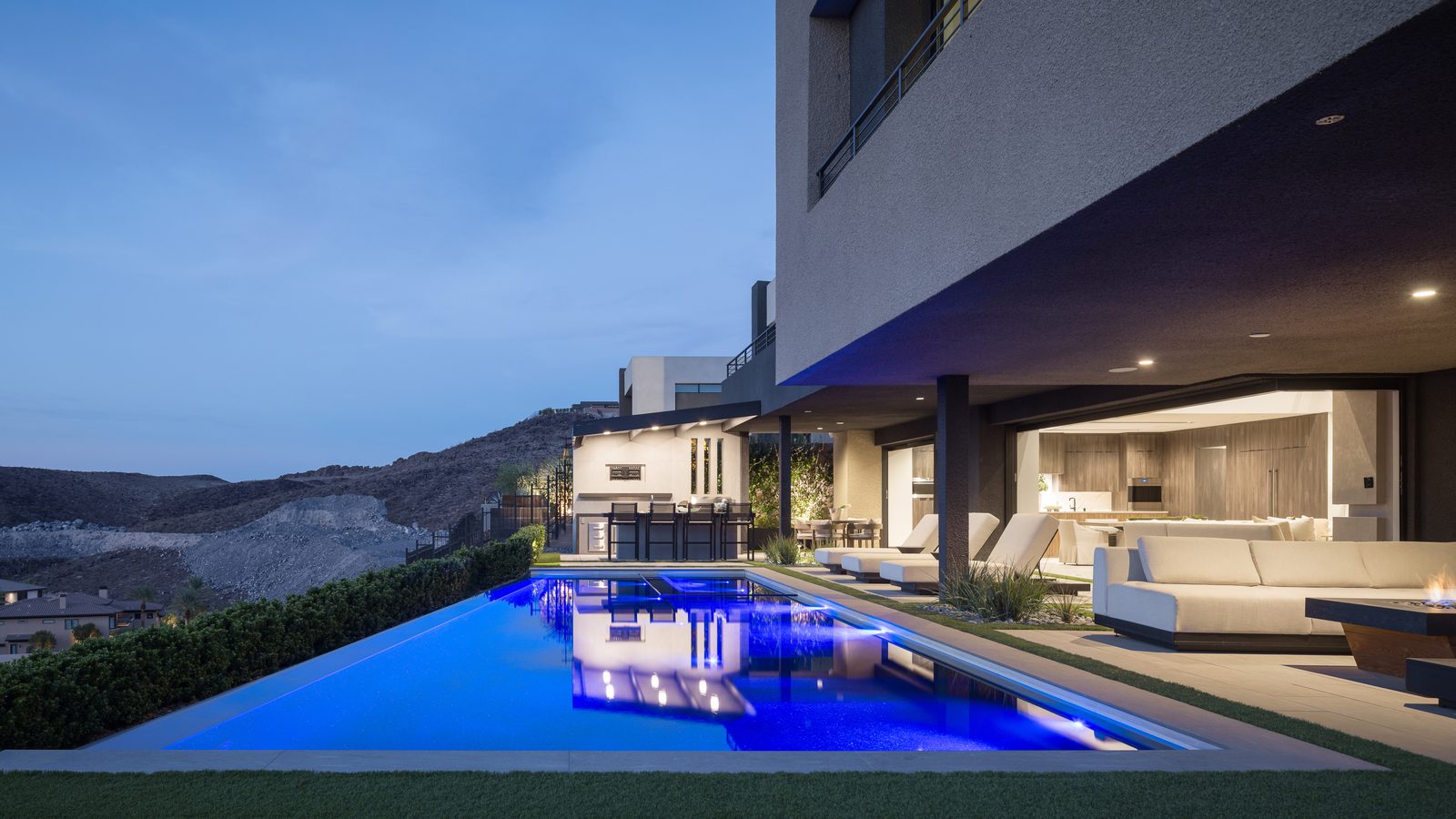Modern Obsidian home with lit pool at dusk