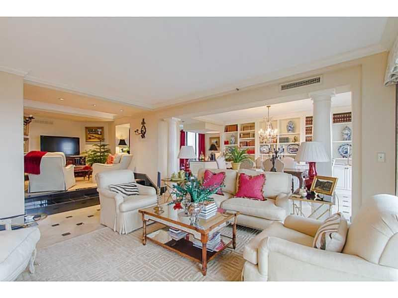 Living room with cream seating, pink pillows, a glass coffee table, and built-in display shelves.