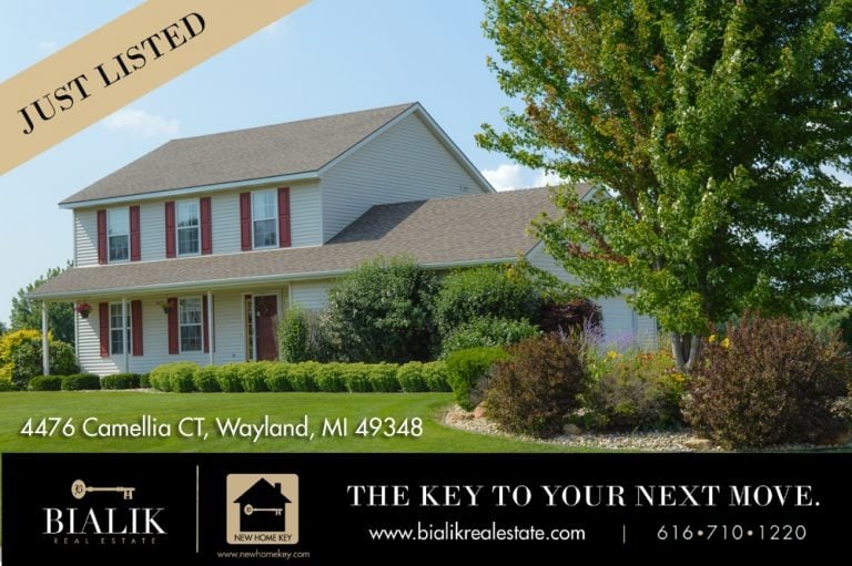 Two-story Wayland home with red shutters, a covered porch, and landscaped front yard.