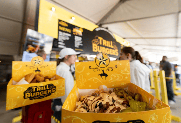 Burger topped with sauce and jalapeños in a yellow Trill Burgers box