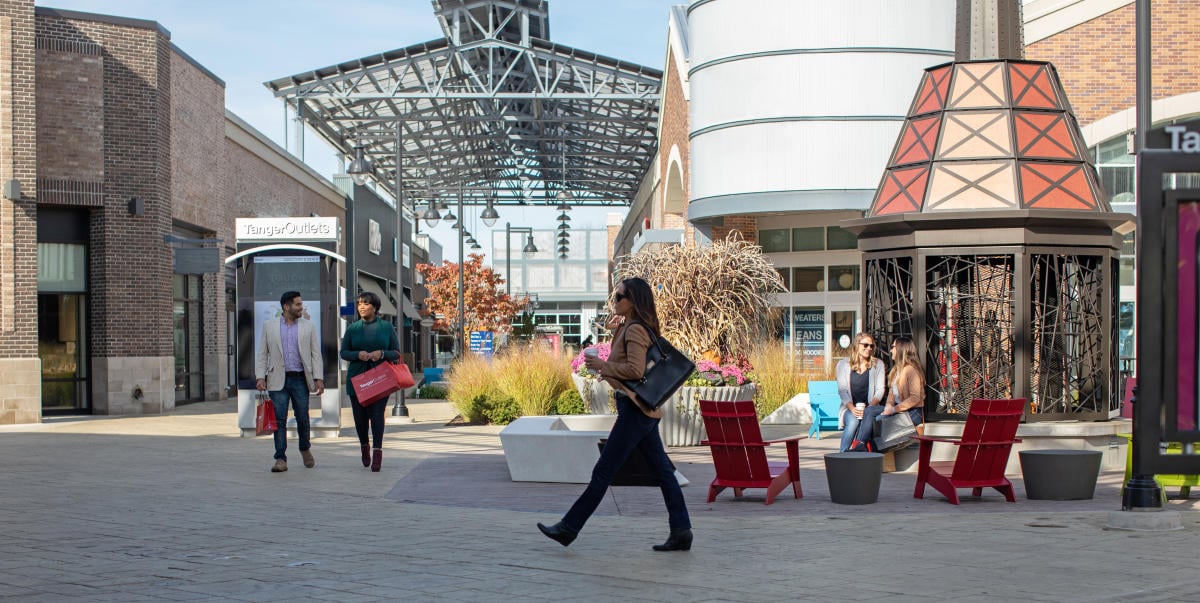 Shoppers walking and sitting at Tanger Outlets in Byron Center, Michigan outdoor mall.