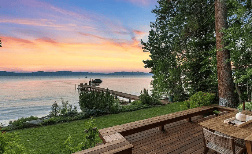 Lakefront deck overlooking Lake Tahoe, with a dock and distant mountains at sunset.