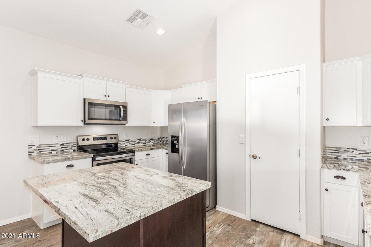 Kitchen with white cabinets, stainless steel appliances, and a large granite-topped island.
