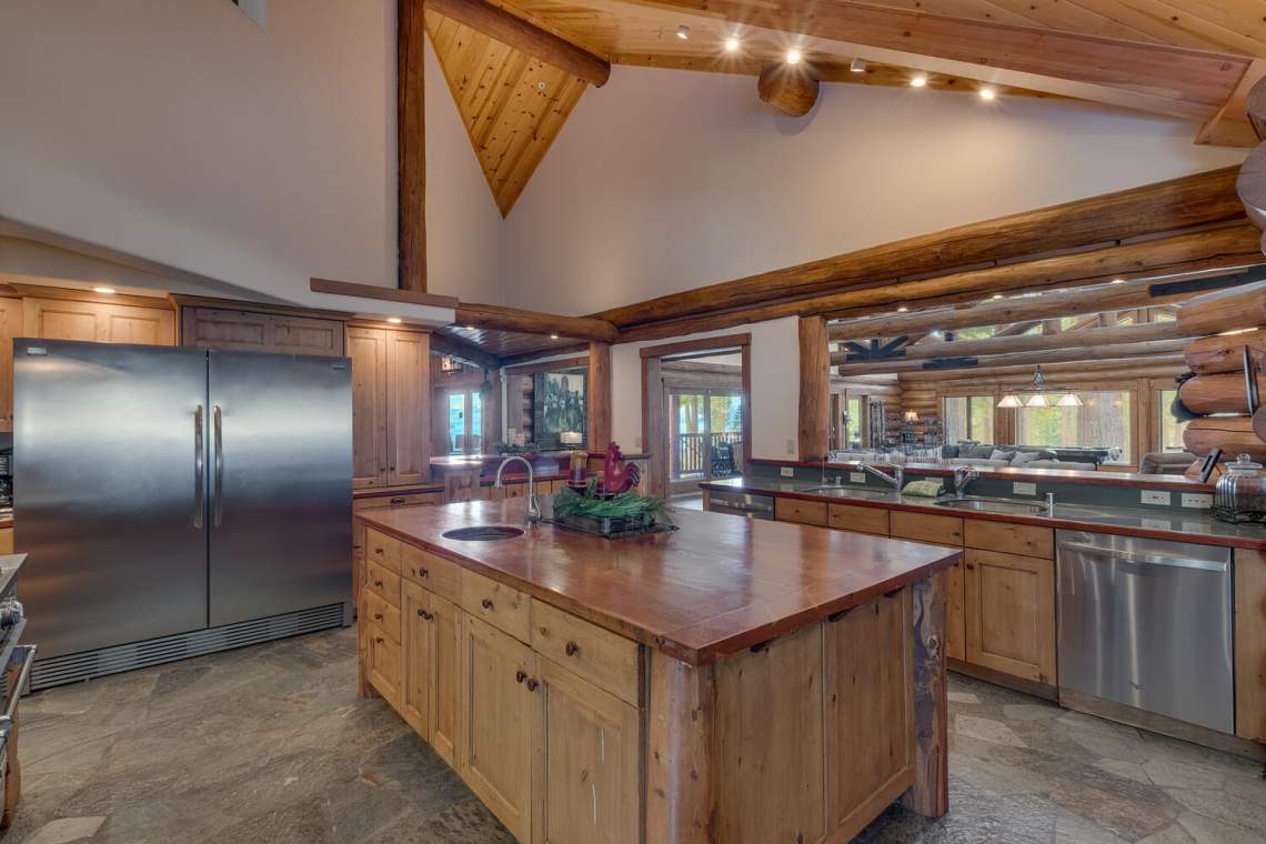 Rustic kitchen with a large wood island, stainless steel appliances, and exposed timber beams.