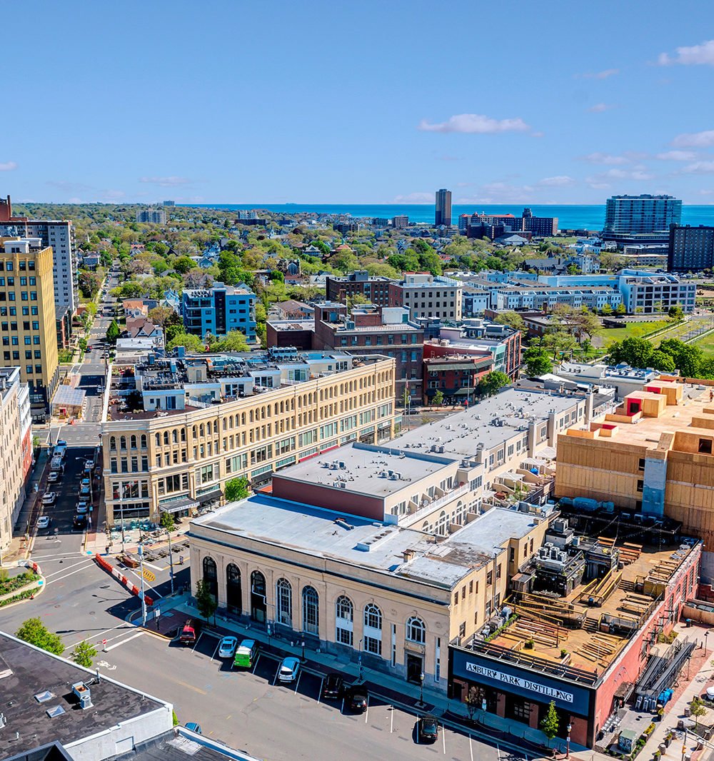 Aerial view of downtown Asbury Park, with rooftops, the ocean, and Asbury Park Distilling.