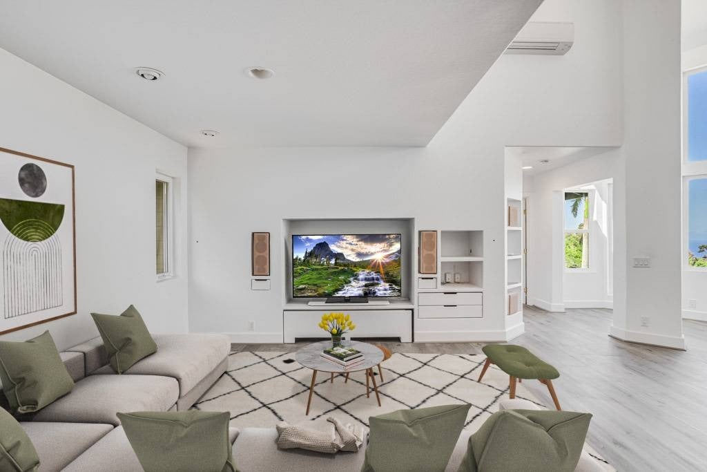 Living room with a pale sectional, green chairs, geometric rug, and built-in television wall.