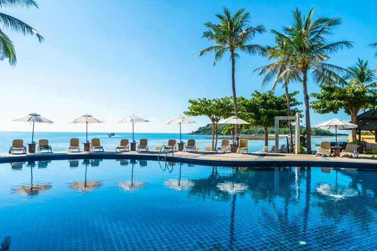 beautiful tropical beach with umbrella chair around swimming pool