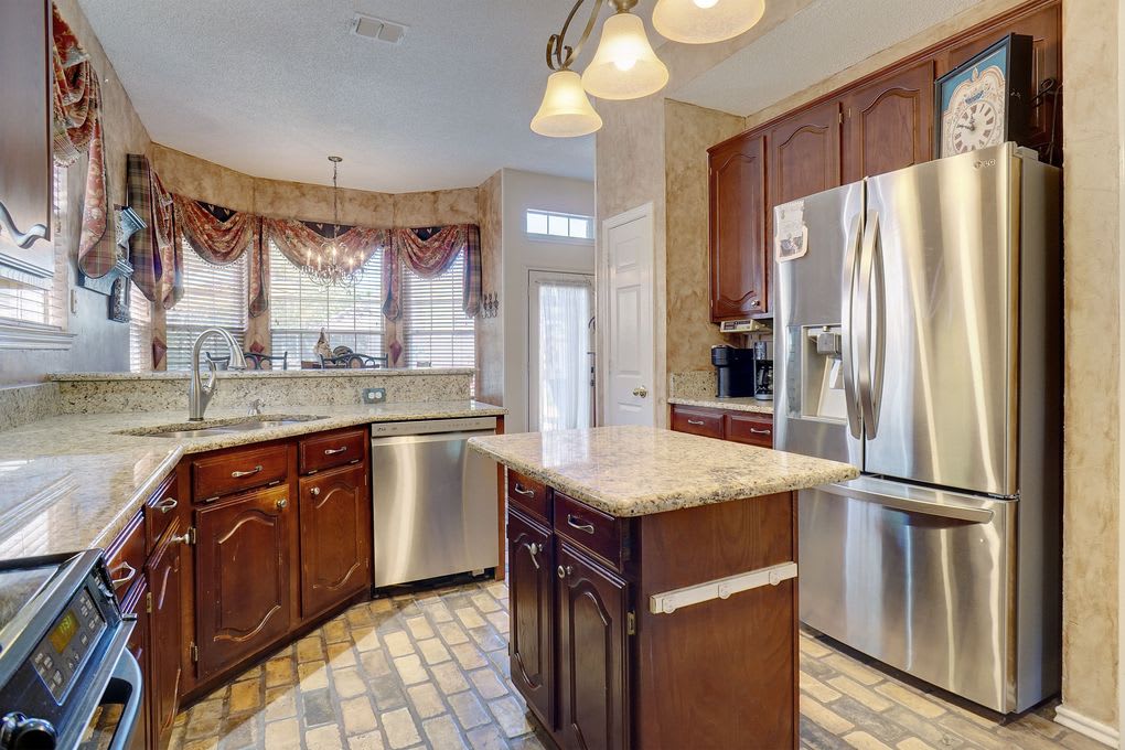 Kitchen with granite countertops, a central island, dark wood cabinets, and stainless steel appliances.