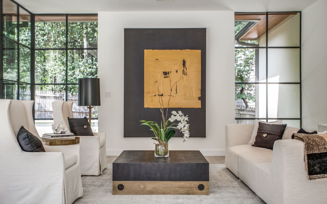 Stunning seating space surrounded by black-framed windows and large black and gold abstract art for a bold and modern look.