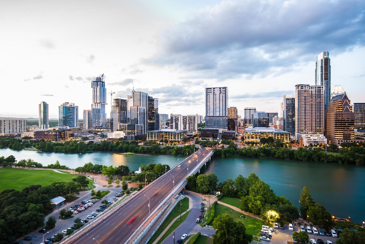 Aerial view of Houston skyline with skyscrapers, bridges, and the Houston Ship Channel in the foreground.