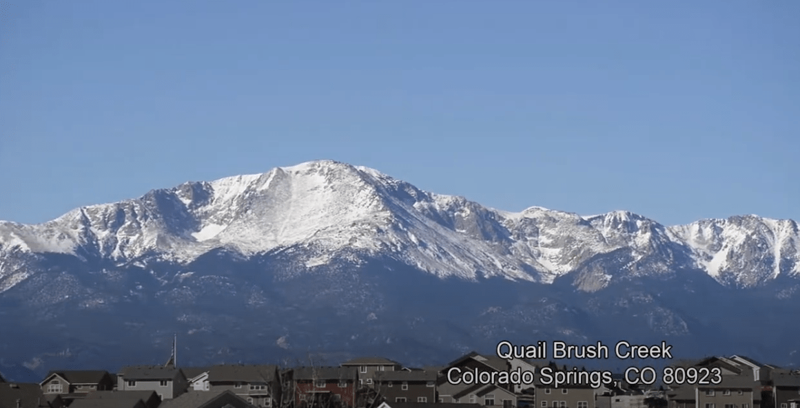 Quail Brush Creek homes beneath a snow-covered mountain range.