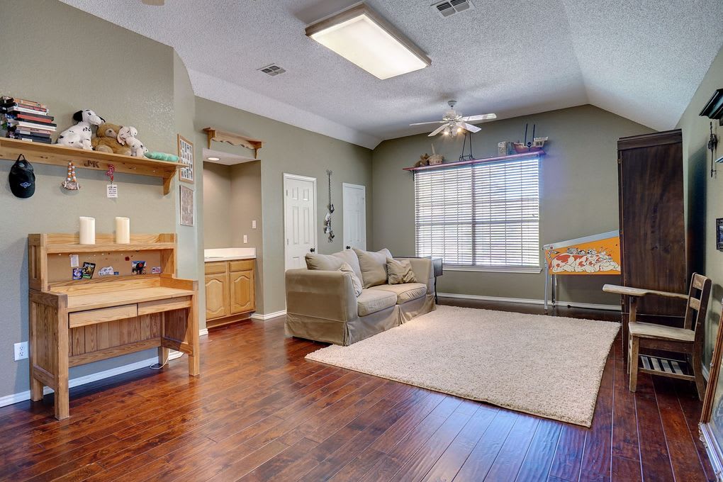 Living room with a beige sofa, large window, dark wood floors, and a wooden workbench.