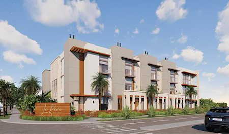 Modern residential building with balconies, palm trees, and landscaped street frontage.
