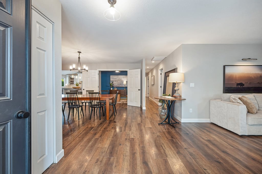 Open-plan dining and living area with hardwood floors and a blue accent wall.