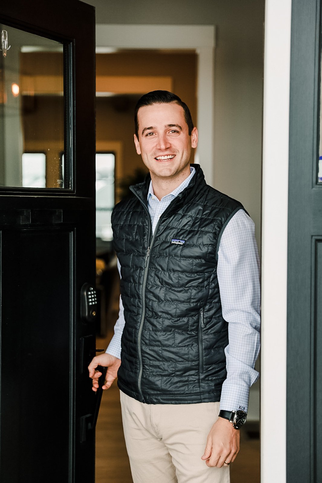 Kevin Schwarz stands in a doorway wearing a black quilted vest and light trousers.