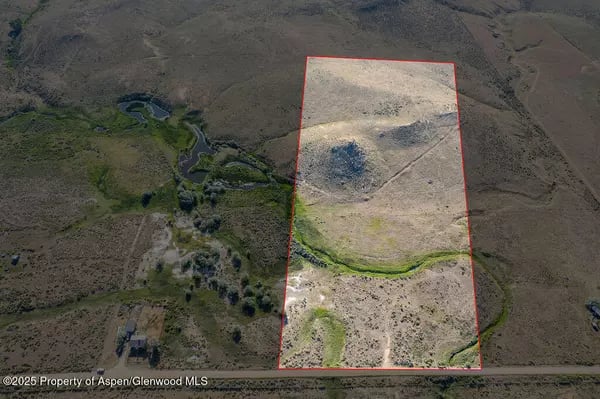Rural land parcel outlined in red, with a winding creek crossing the open terrain.
