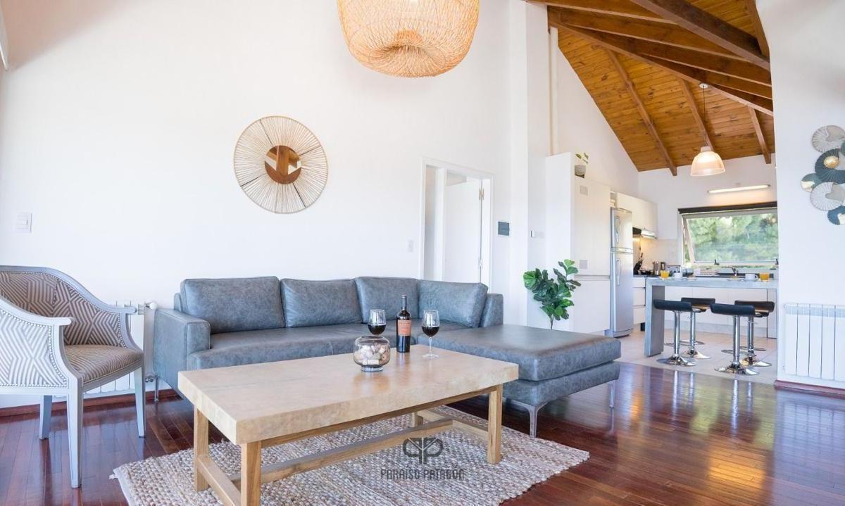 Apartment living room with gray sectional, wooden coffee table, and vaulted wood ceiling beside the kitchen.