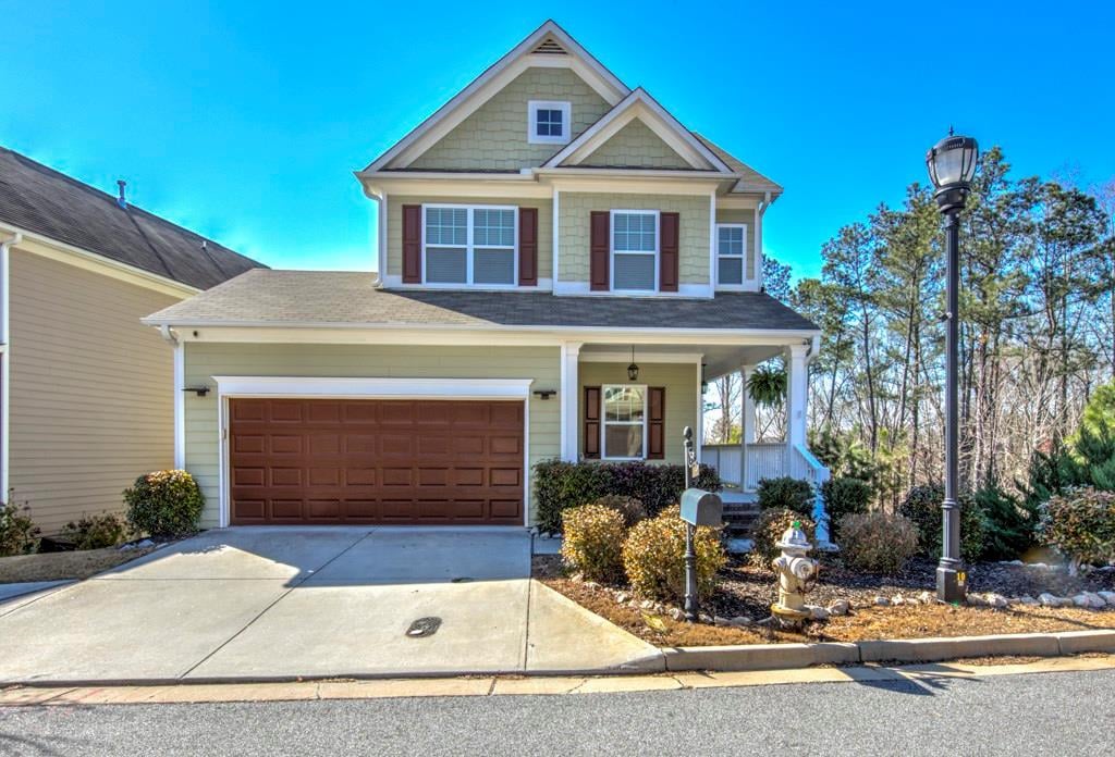 Two-story beige house with brown shutters, a double garage, and a covered porch.