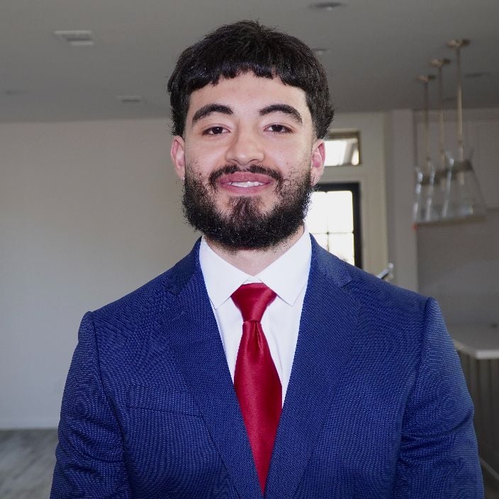 Joshua Torres in a blue suit and red tie