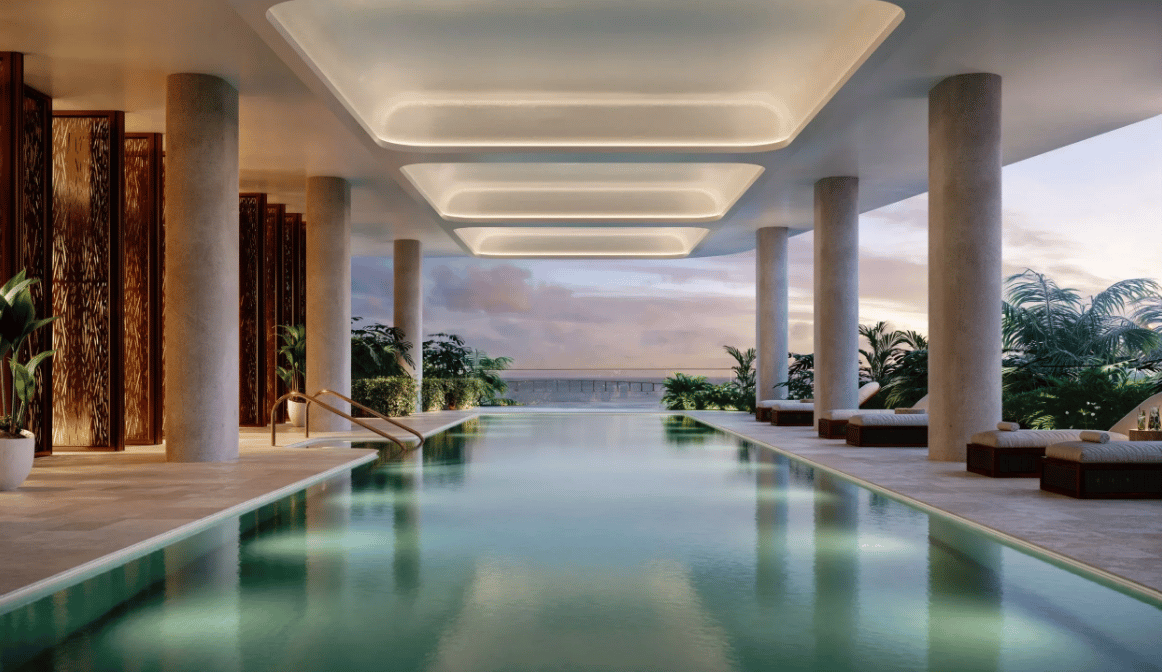 Swimming pool beneath a covered terrace, with tropical landscaping and lounge seating overlooking the water.