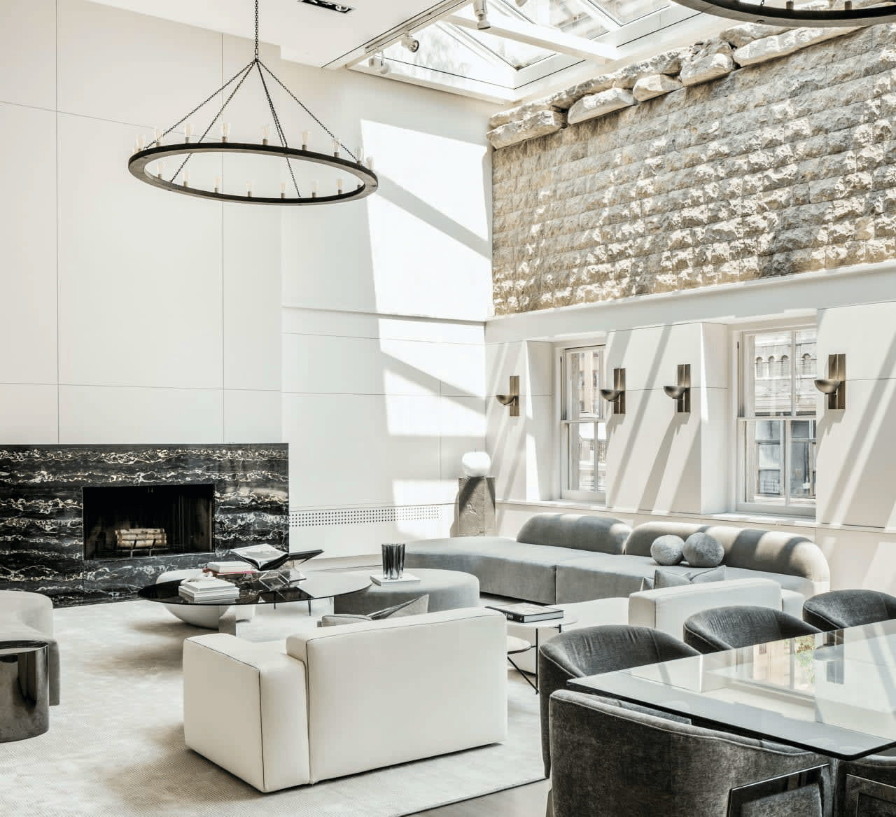 Bright living room with a skylight, stone accent wall, and black marble fireplace.