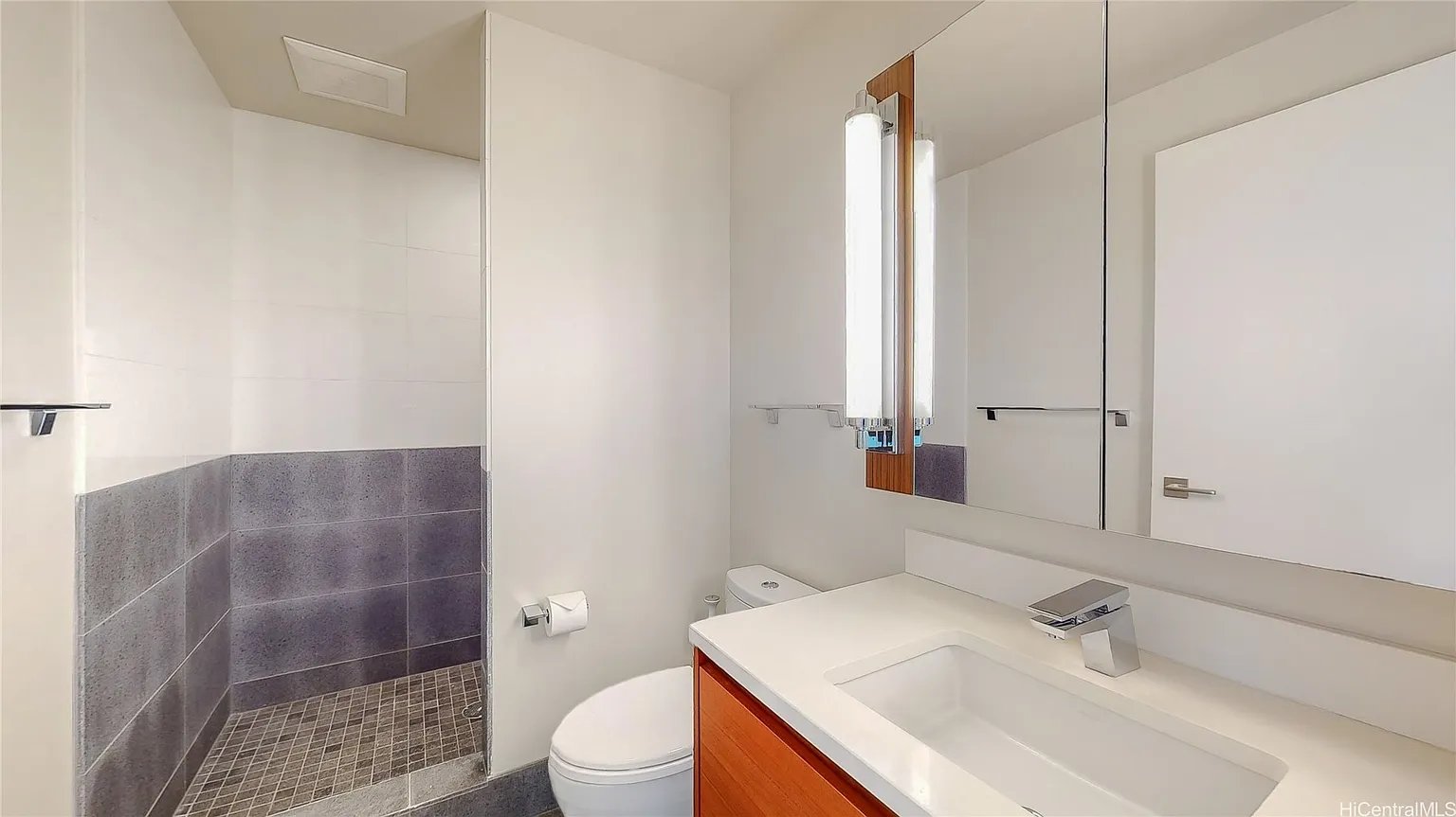Modern bathroom with a tiled walk-in shower, white vanity, and orange-brown cabinetry.