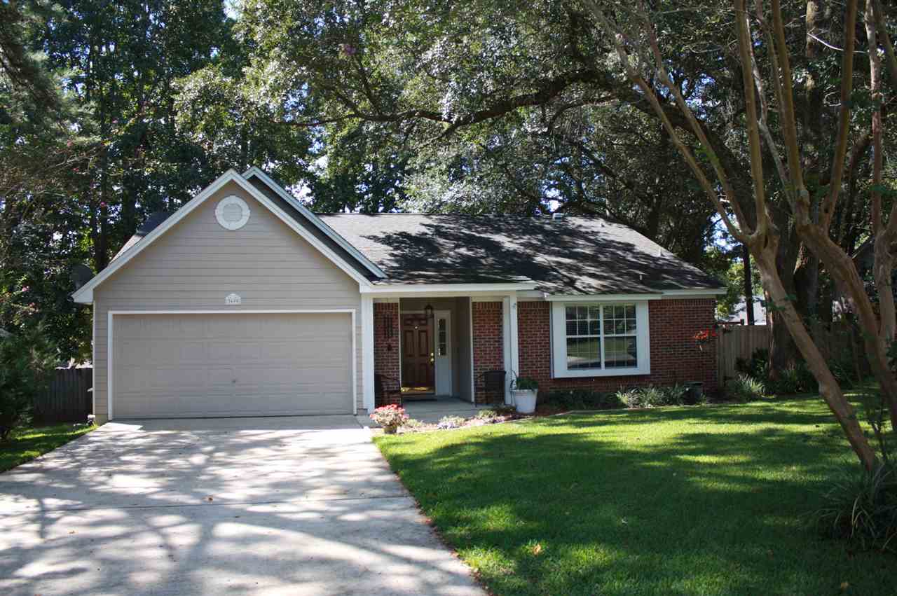 A brick home featuring a garage and a well-maintained driveway.