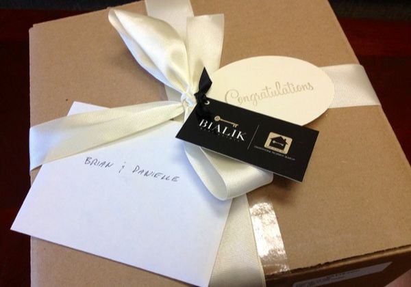Gift box with a cream ribbon, a congratulations tag, and a card addressed to Brian and Danielle.