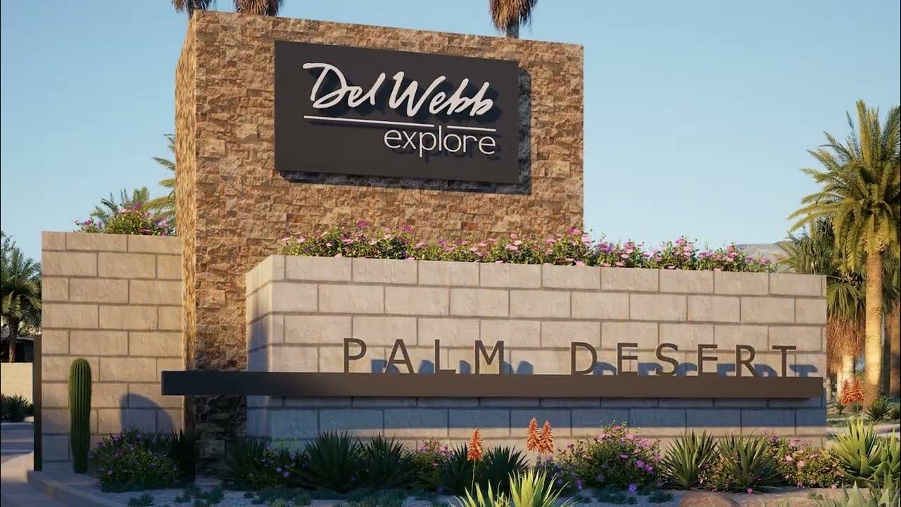 Del Webb Explore entrance sign in Palm Desert, framed by palms and desert landscaping.