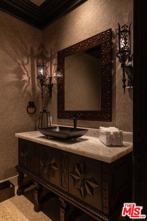 Powder room with a carved dark vanity, stone countertop, vessel sink, and ornate mirror.