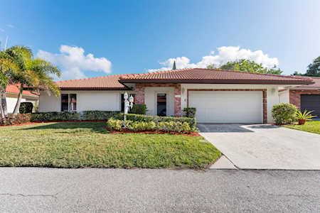 Single-story ranch home with a tile roof, brick accents, front lawn, and wide garage.