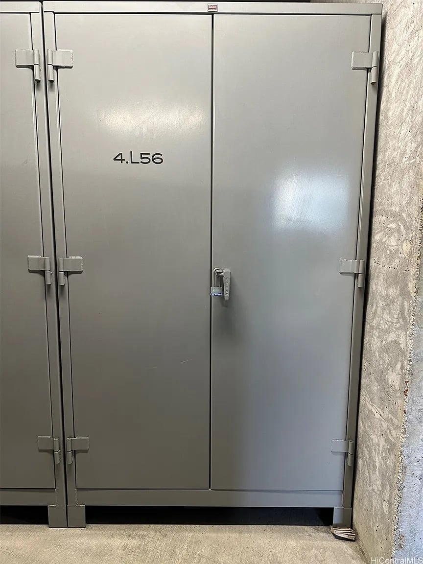 Gray metal storage locker marked 4.L56 beside a rough concrete wall.