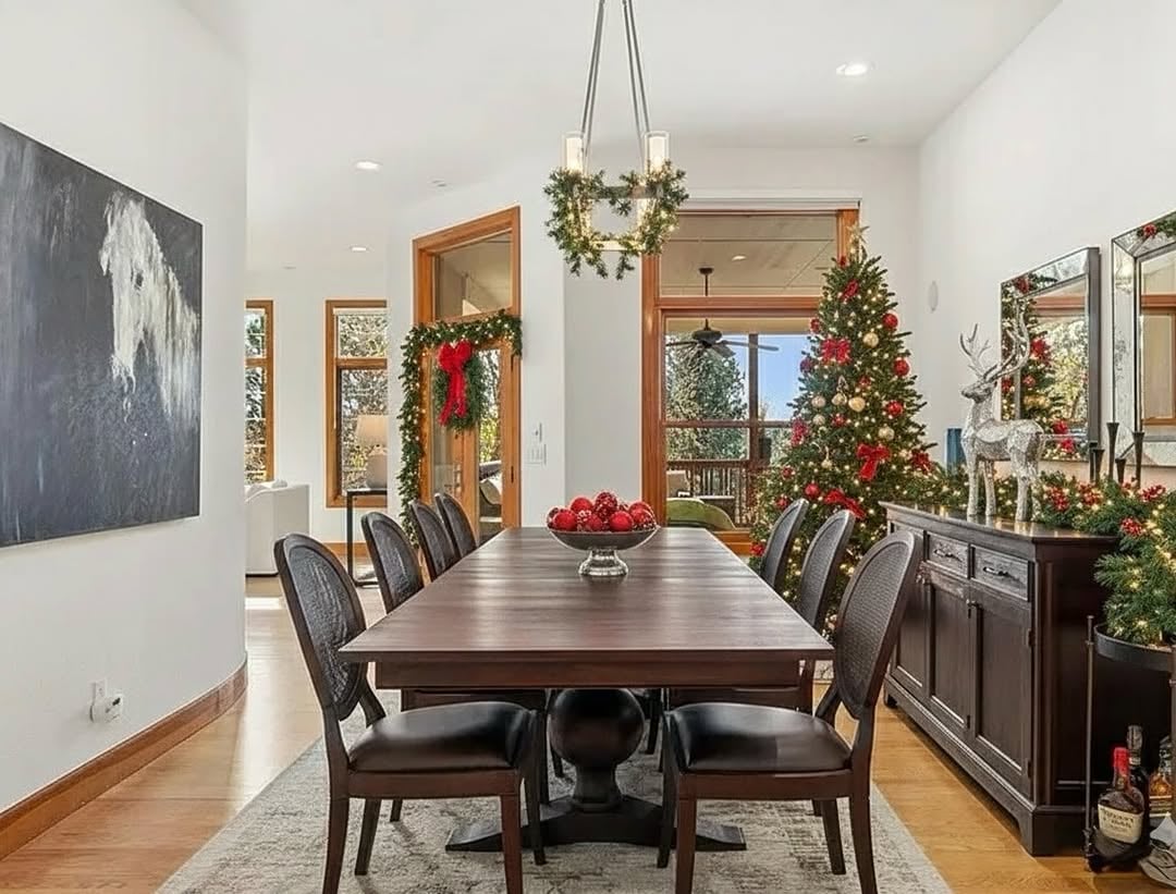 Elegant holiday dining room in a Parker, Colorado estate, with a long table set for Christmas, large windows, and views of snowy trees outside.