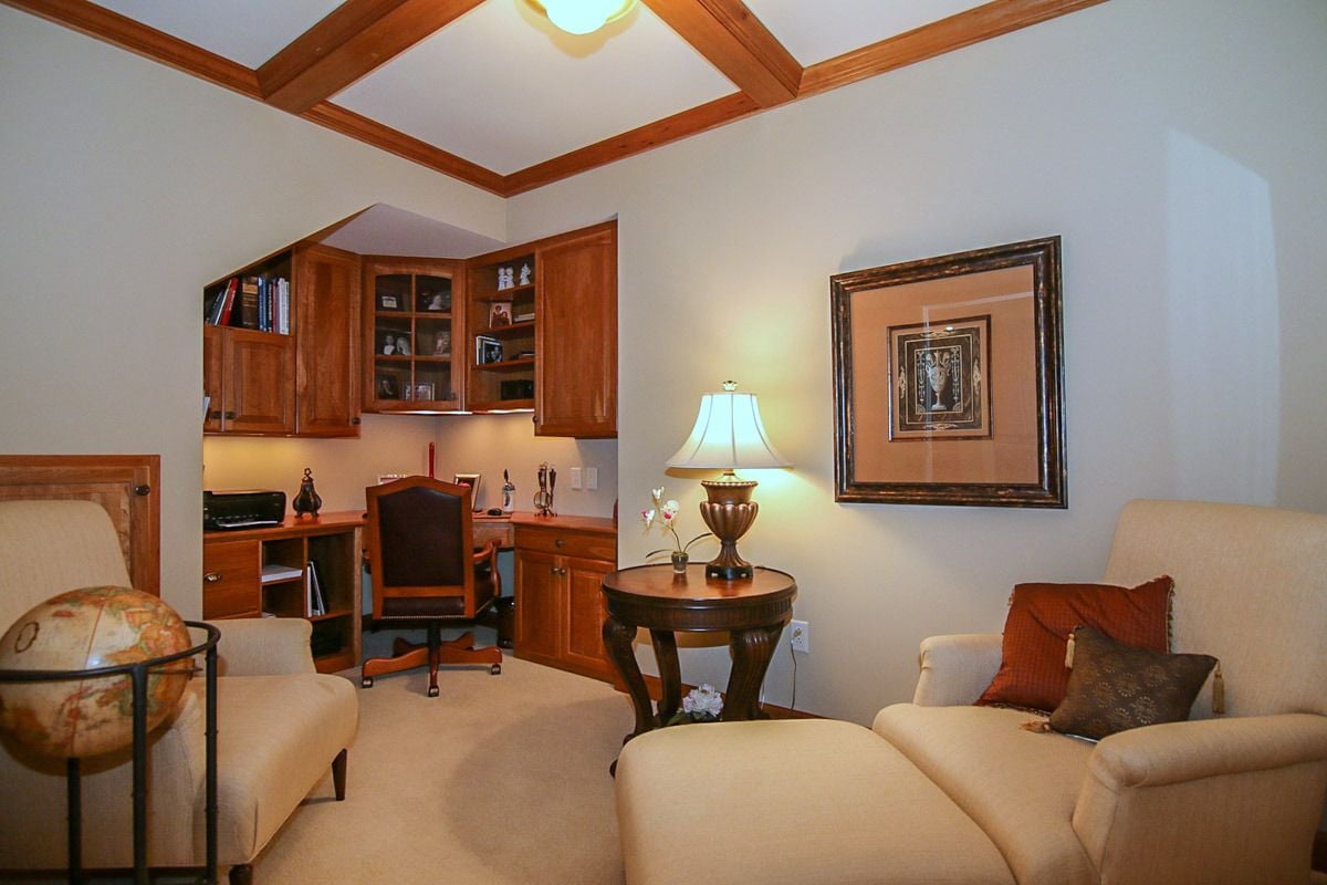 Penthouse den with built-in wooden desk, cream seating, and a coffered wood ceiling.