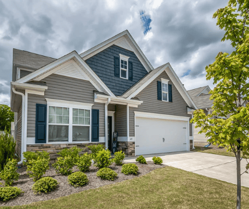 Gray-sided house with blue shutters, multiple gables, and a white double garage door.
