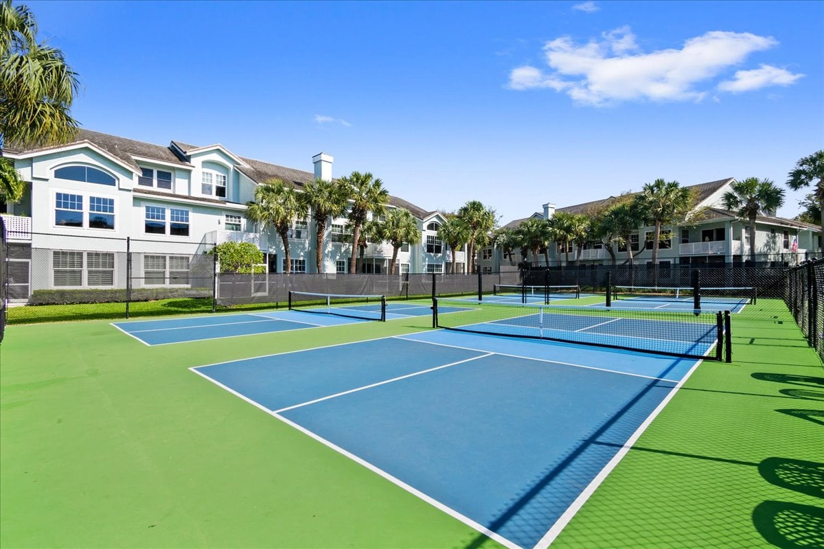 Pickleball courts in front of Sea Colony condominium buildings and palm trees.