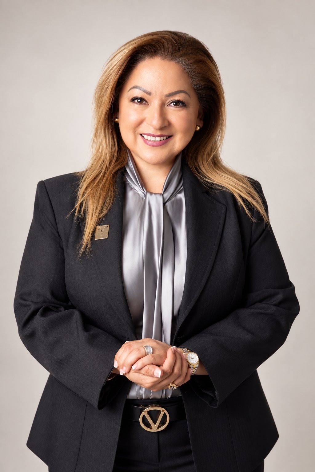 Erika Jacott-Strum smiling in a black suit and silver blouse, hands clasped.
